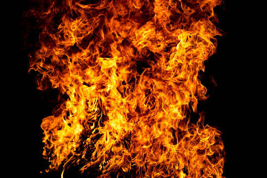Flame burns through orange flames. Flame surrounds blazing flames. Creative flame with fire. Burning flame beside fire.