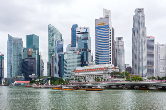 Singapore&rsquo;s Central Business District skyline from Marina Bay featuring modern skyscrapers, historic Fullerton Hotel and Esplanade Bridge under overcast sky in Southeast Asia