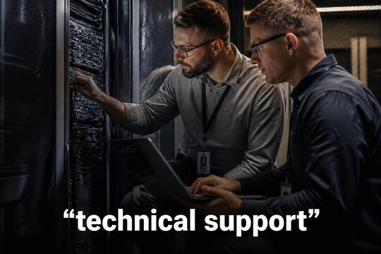 Two men in a server room are looking at a laptop, suggesting technical support.