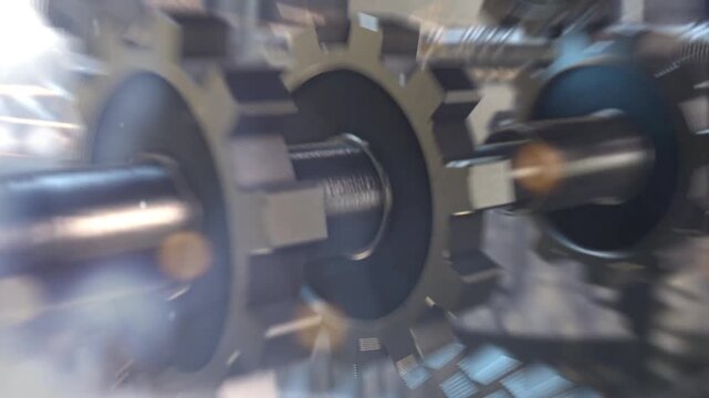 Gears rotate rapidly in a close-up motion shot highlighting the mechanical interaction of sharp metallic teeth spinning together as part of an industrial engine system during heavy duty active usage.