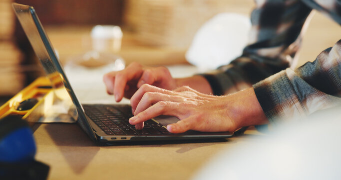 Typing, man and hands of carpenter with laptop in workshop for research on industrial project. Technology, email and woodworker with computer for feedback on furniture manufacturing in factory.