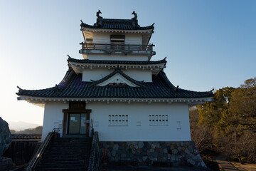 Fototapeta premium KITSUKI, OITA, JAPAN - FEBRUARY 17, 2025: Frontal view of Kitsuki Castle main keep with stone foundation and traditional tile roof against a clear sky in Oita Prefecture, Kyushu.