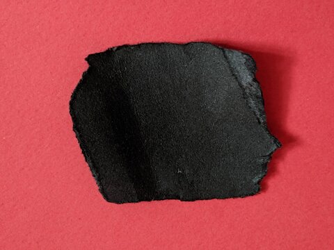 Black irregular ripped paper on vivid red background, highlighting abstract texture and bold contrast for creative visual concepts.