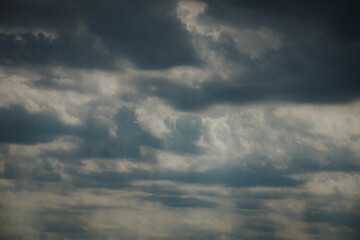 Obraz premium Dark storm clouds with varying shades of gray and white, creating a dramatic sky texture, illuminated by soft light filtering through the cloud layers