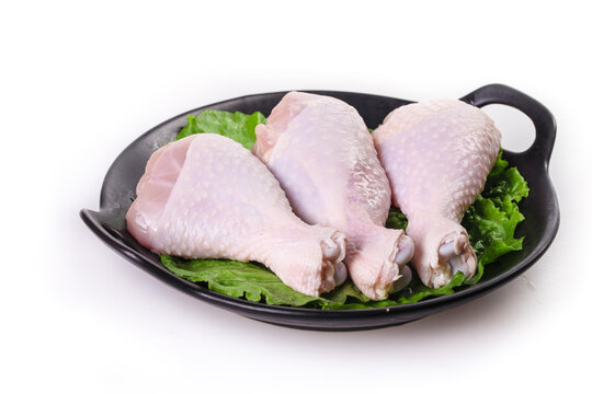 Raw Chicken Legs and Thighs on Black Plate with Lettuce Garnish for Supermarket Display