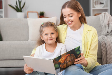 Naklejka premium Little girl with her mother reading book at home