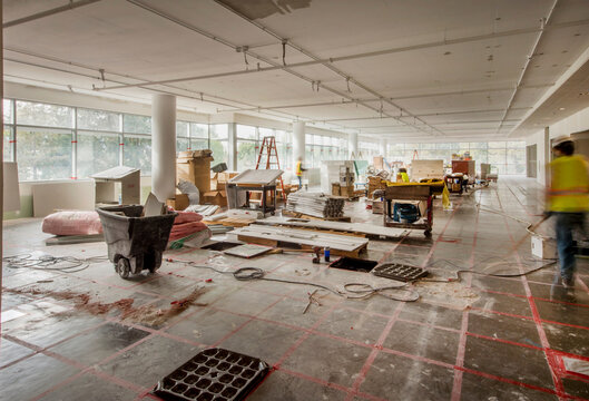 Under construction commercial interior space with unfinished flooring and exposed ceilings hard hat construction