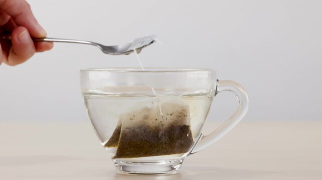 Hand Steeping Herbal Tea Bag in Glass Cup with Spoon