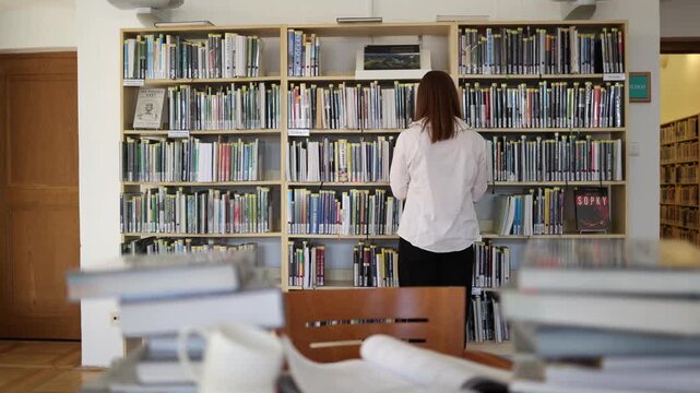 Woman becomes fascinated by an unexpected discovery in a library book and keeps reading with growing curiosity after opening a random page while browsing the shelves alone