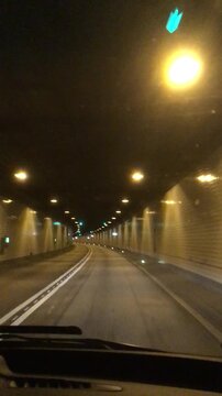 Driving through the multi lane Elbtunnel in Hamburg, showing illuminated tunnel walls, ceiling lights, road markings and an empty roadway stretching ahead in Germany