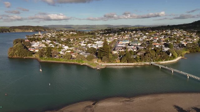Aerial view over coastal Raglan town peninsula and footbridge surrounded by estuary water, New Zealand