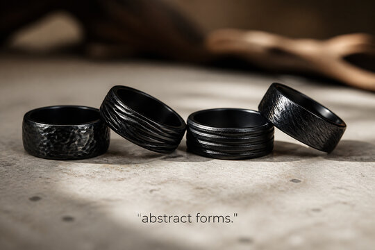 Several black metal rings are displayed on a light-colored surface against a blurred background.