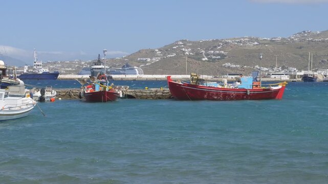 Fishing boats anchored in Mykonos harbor with breakwater and Aegean Sea Greece