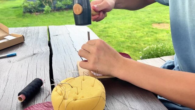 Close-up of hands stitching leather outdoors using specialized tools. Perfect for DIY tutorials, craft workshops, artisanal branding, and hobby content.