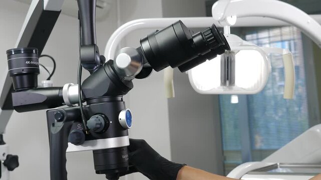 Female hand in black glove lifting heavy dental microscope from bottom to top, slowly filling camera frame. Professional medical equipment manipulation in modern stomatology clinic 4k video