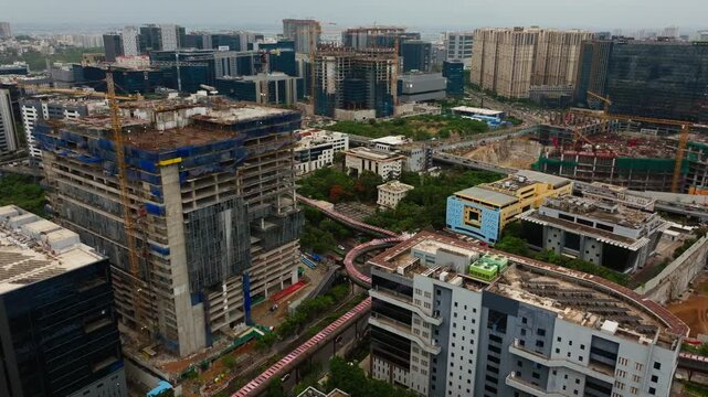 Active construction high-rise building with tower crane, skywalk, Qualcomm Building and corporate offices at mindspace, madhapur, hyderabad, telangana, india. day time, crane shot, drone shot, 4k.