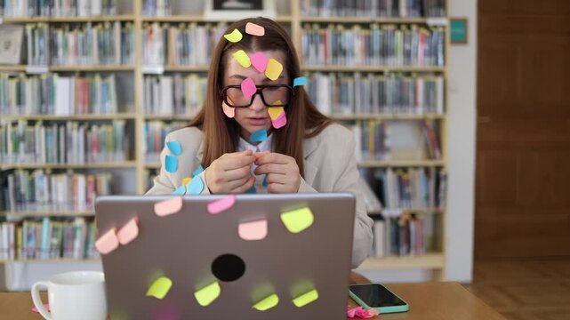 Overworked office employee sorts sticky note reminders while facing an endless task list at her laptop showing mental overload from excessive workload and tight deadlines