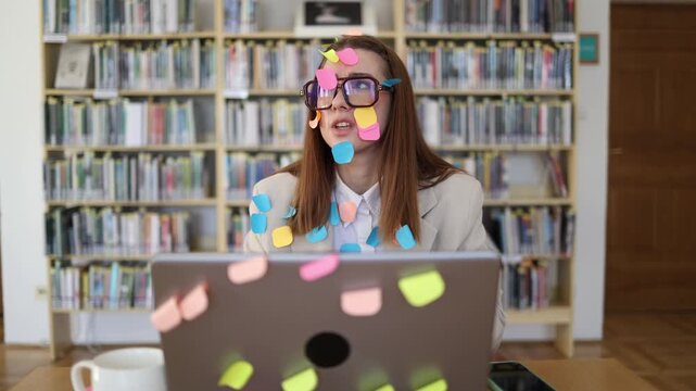 Overwhelmed office worker covered in sticky note reminders struggles to manage a growing task list while working on laptop under pressure from deadlines and workload