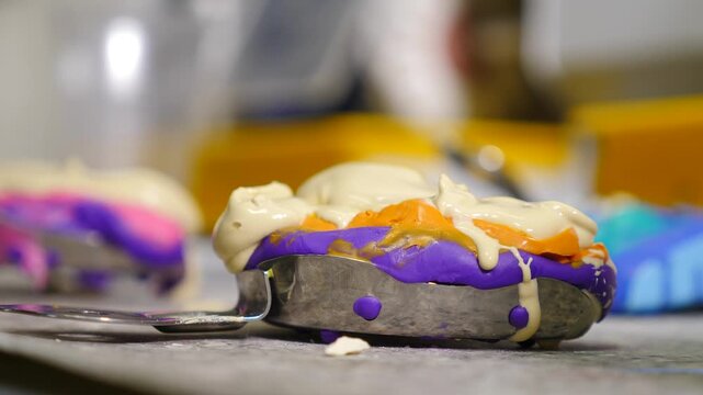 Dental technician pouring creamy white liquid gypsum over colored jaw impression mold. Creating precise plaster cast essential for fabricating custom crowns and prosthetic restorations in lab. 4k