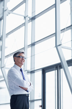 Thinking, smile and arms crossed with business man in office for vision, insurance broker and ceo. Portfolio manager, reflection and claims advisor with mature employee in agency for risk management
