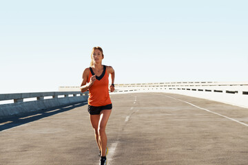 Obraz premium Workout, woman and running for fitness in road with pace training, morning cardio and practice. Space, serious athlete and jog on highway bridge for exercise routine, endurance or health and wellness