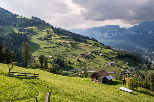 Idyllische Schweizer Alpenlandschaft mit gr&uuml;nen Weiden, Bergh&uuml;tten und Gebirge im Hintergrund