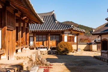 Fototapete Braun Sunny Courtyard View of Traditional Korean Hanok Wooden Buildings, Tiled Roofs, and Mountain Background  © n3moh3ro