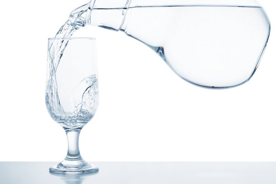 clear water pouring from decanter into transparent glass isolated on white background