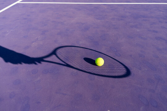 Tennis ball on court with racket shadow