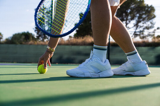 Close up of person picking up tennis ball on tennis court