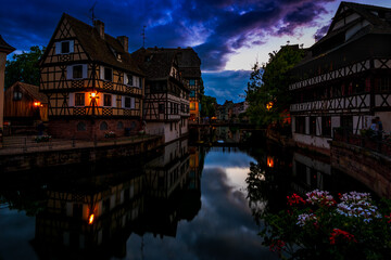 Obraz premium Half-timbered houses beside a canal with reflections under a dramatic blue hour sky