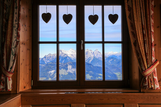 Austrian Alps Lofer Steinberger viewed from a traditional wooden chalet window with hanging heart decoration.