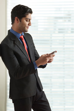 Young businessman texting on mobile phone