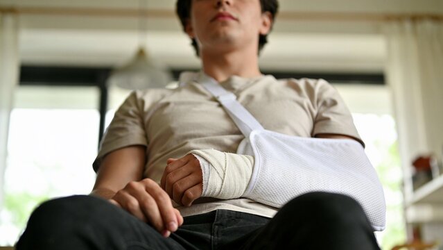 Close Up Of Injured Arm In White Cast Supported By Medical Sling
