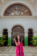 Fototapeta premium Elegant Portrait of an Indian Woman Wearing a Pink Saree Inside an Art Gallery