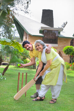 Senior woman playing cricket with her son