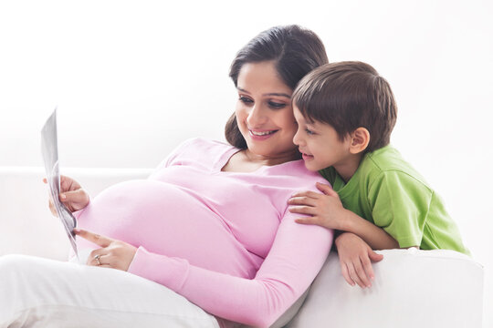 Pregnant mother and son looking at ultrasound scans