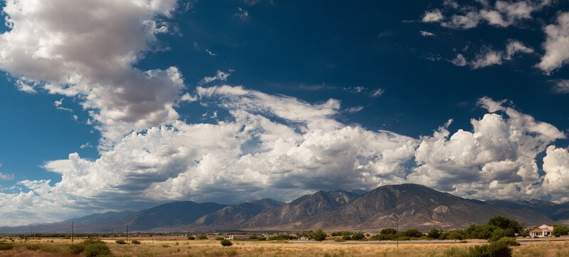 Dramatic Clouds Over Arid Landscape - A Majestic Mountain Backdrop.