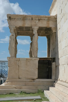 A detailed side view of the historic sculpted stone Caryatid statues supporting the ancient roof structure of the Erechtheion temple on the Acropolis in Athens Greece.