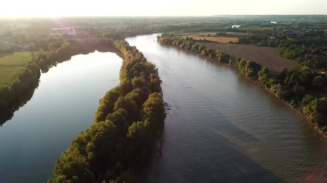 Aerial view of the Mascaret tidal bore wave rolling along the Garonne river near Podensac, with lush trees lining the riverbanks in Mascaret Podensac, Nouvelle-Aquitaine, France.