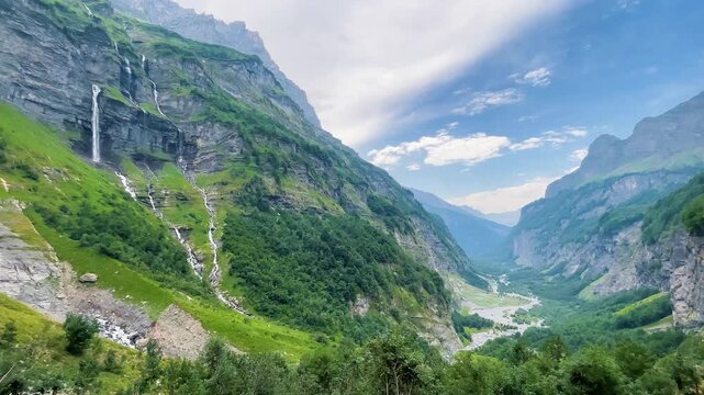 Scenic mountain valley landscape with high waterfall cascading down steep cliff under partly cloudy sky- Samoens Sixt Fer &agrave; cheval