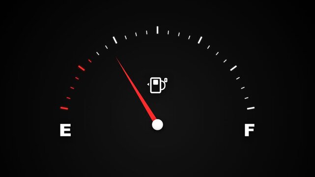 A low fuel indicator glowing on the dashboard displays the current gas level status inside a vehicle to warn the driver that the tank requires an immediate refill at the next available station