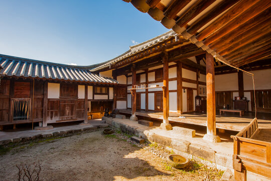 Traditional Korean hanok architecture upward view of wooden pillars, eaves, and tiled roofs against blue sky
