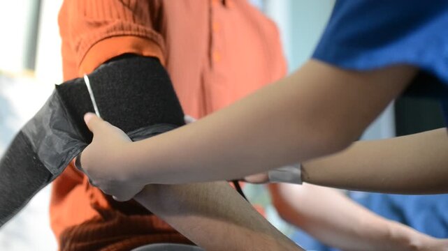 Doctor checks patient's blood pressure with cuff and stethoscope in a medical
