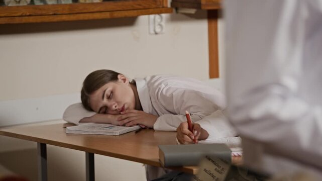 Senior Caucasian male professor walking in anatomy classroom, tilting down to young female student sleeping at desk. Clip is ideal for projects on student burnout or academic pressure