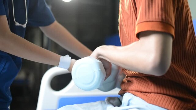 Physical therapist guides male patient using dumbbells for strength training. Person works out arm muscles in clinic. Patient performs rehabilitation exercises for recovery and mobility.