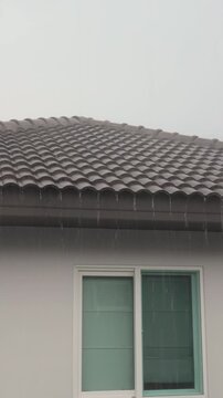 Heavy rain falling on dark roof tiles of modern house during stormy weather