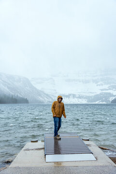 Smiling man stands on a snowy dock by Cameron lake in Waterton