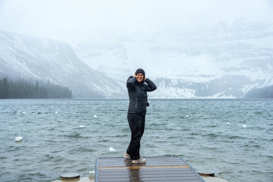 Happy woman stands on a pier in Cameron lake during winter weather