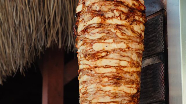 Traditional Turkish chicken doner kebab roasting on a vertical rotisserie at a street food stall. Marinated layers of meat slowly cooking on a rotating spit, ready to be sliced for shawarma and durum